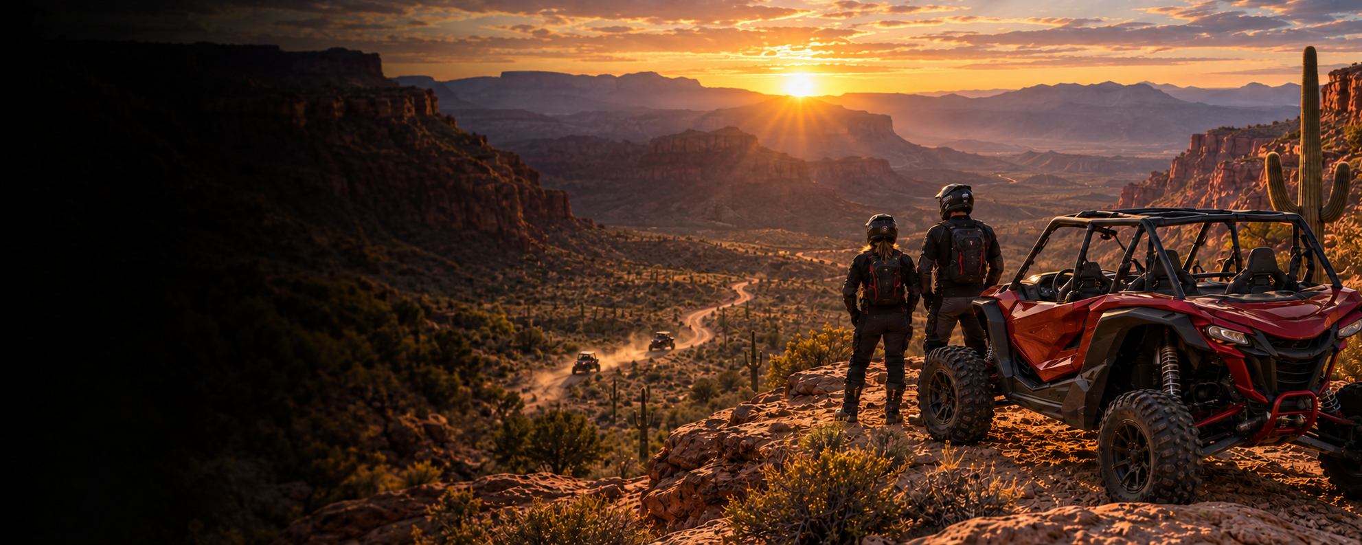 Two riders beside a red UTV overlooking an Arizona canyon at sunset as more UTVs kick up dust on the trail below